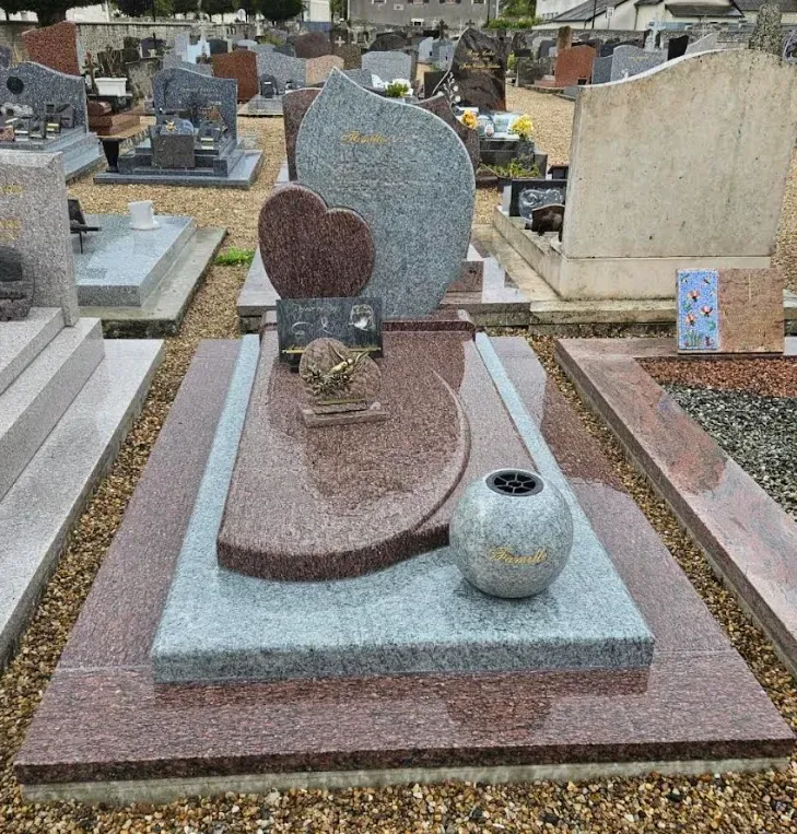 Monument funéraire moderne en granit rose et gris avec motif cœur au cimetière.