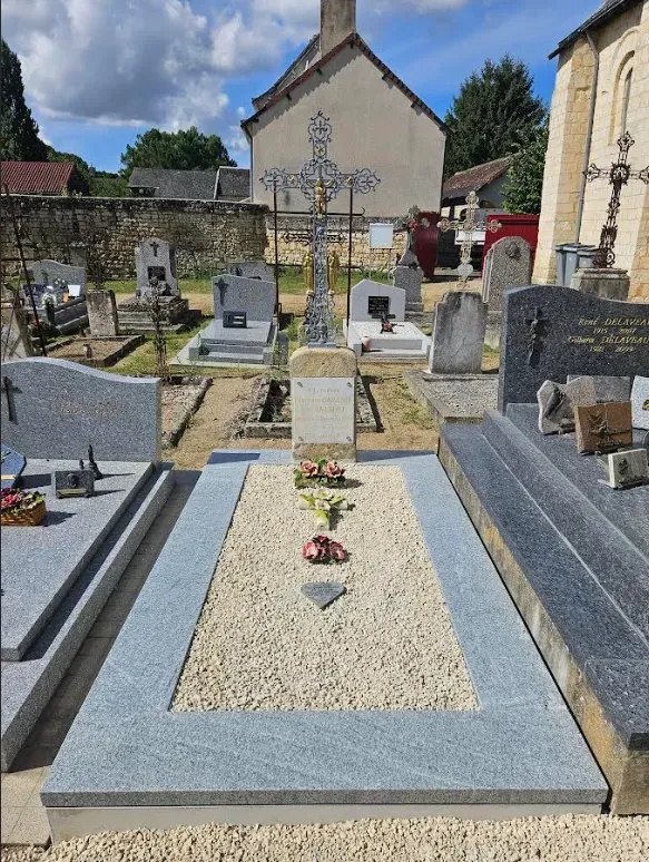 Sépulture ancienne rénovée au cimetière avec une croix métallique ouvragée
