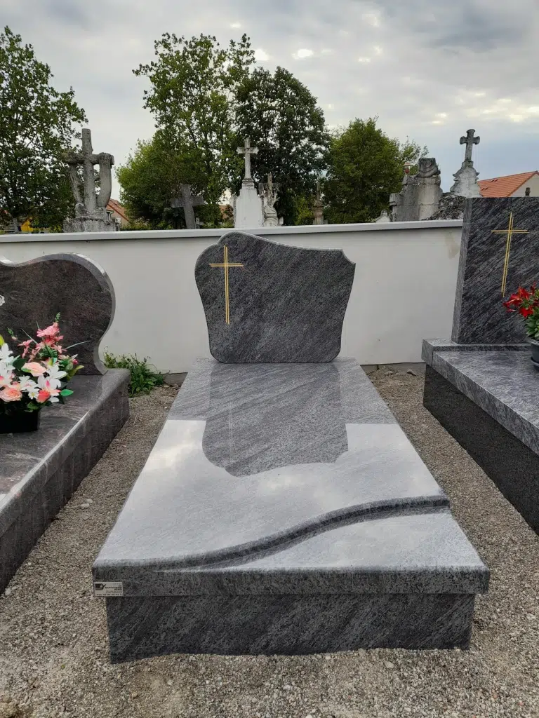 Monument funéraire en granit gris poli avec une croix dorée sur la stèle.